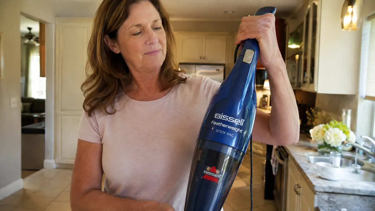 Hand lifting the lightweight Bissell Featherweight vacuum with one arm off a hard floor