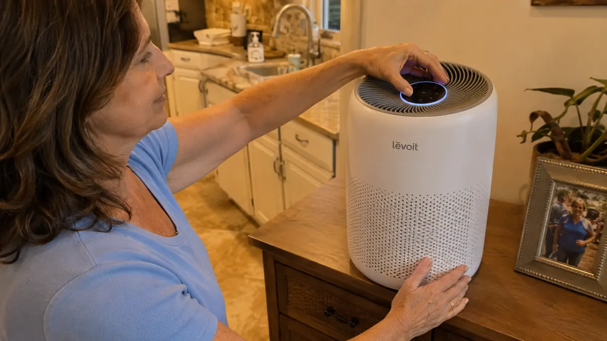 Hand plugging in and adjusting the dial on the Levoit Vital 200S air purifier on a bedroom dresser