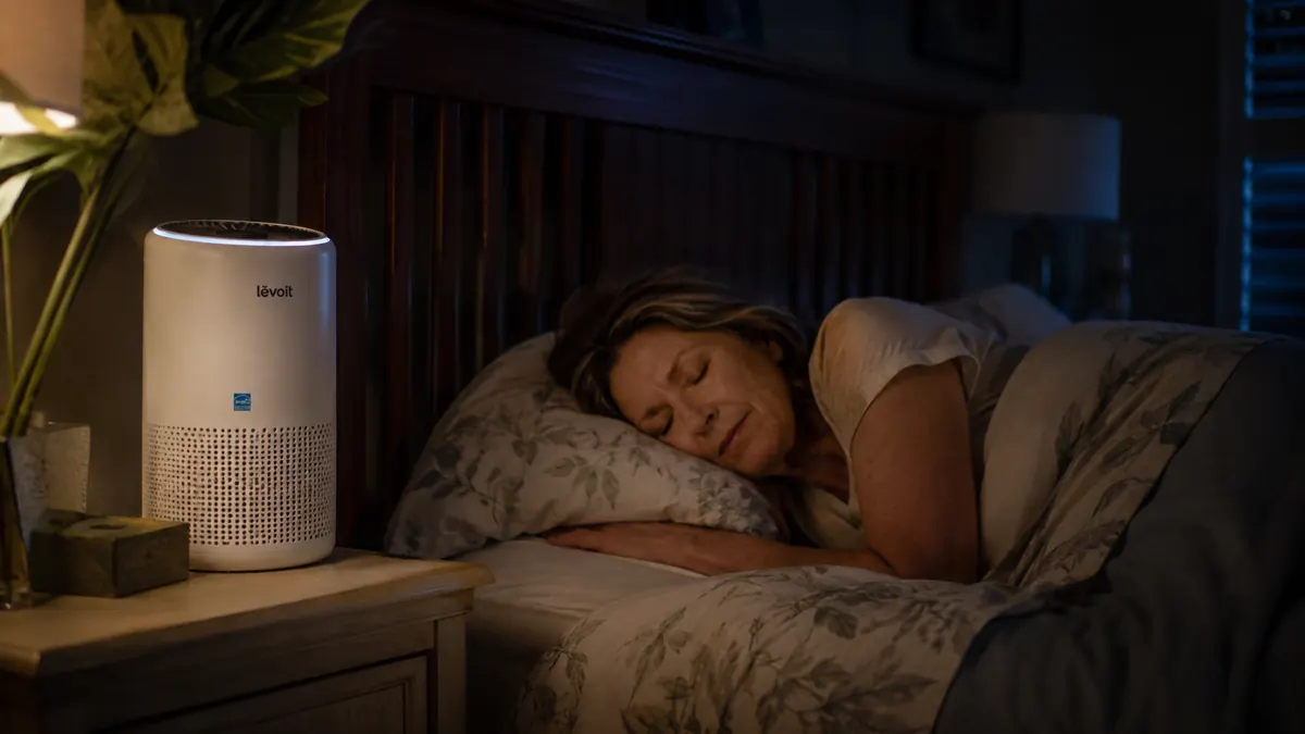 Levoit Vital 200S air purifier glowing softly on a nightstand in a dark, quiet bedroom at night