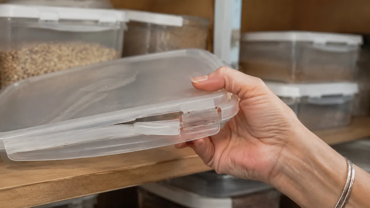 A cracked latch hinge on a Vtopmart container lid propped against a pantry shelf, lid slightly ajar